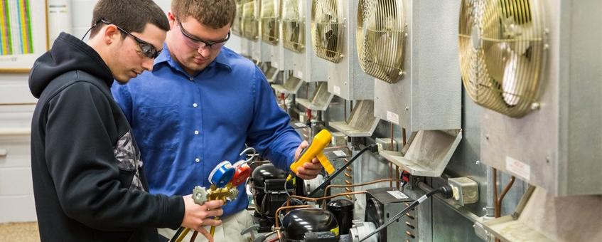 Two HVAC students interpret information from the equipment in their class.